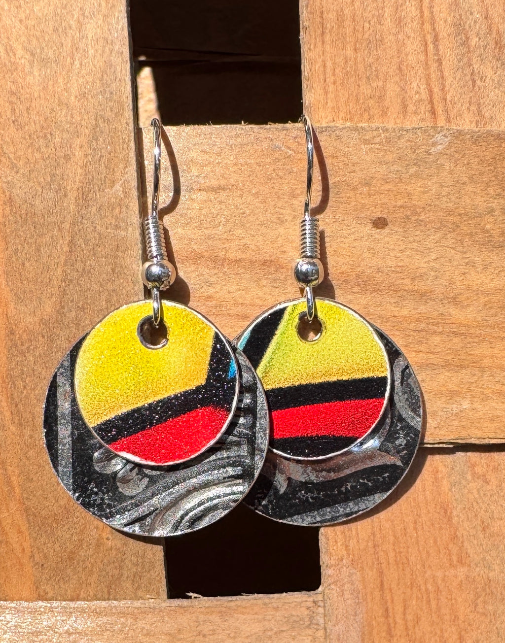 Bold two-layer circle drop earrings with yellow, red and black stripes on a black and silver marbled base