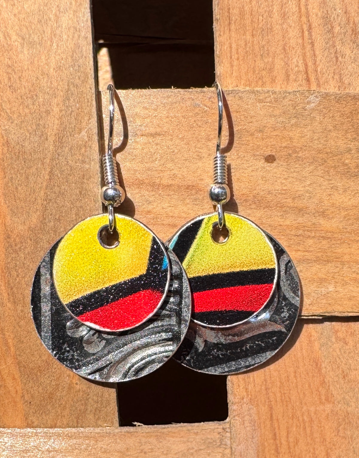 Bold two-layer circle drop earrings with yellow, red and black stripes on a black and silver marbled base